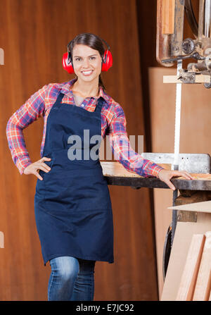 Zuversichtlich Zimmermann mit Hand auf Taille durch Bandsäge Stockfoto