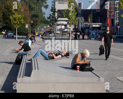 Straße Betonmöbel mit jungen Menschen in der Sonne entspannen und Benutzung von Mobiltelefonen am Kölner Bahnhof, Deutschland Stockfoto