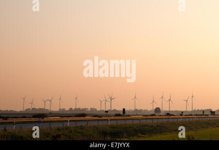 Windmühlen entlang der Autobahn 31 in Norddeutschland in der Nähe der Stadt Leer während des Sonnenuntergangs Stockfoto