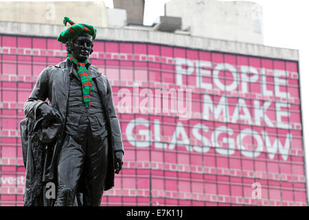 Eine Statue des schottischen Dichters Robert Burns mit einem Tartan Hut und Schal vor den Menschen gemacht Glasgow Zeichen, George Square, Glasgow, Schottland, Großbritannien Stockfoto