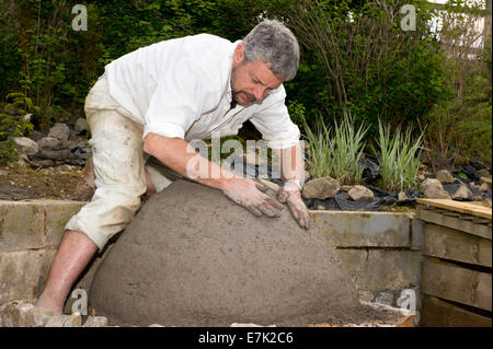 Erde-Ton-Cob-Ofen-Projekt. Die erste Schicht aus Ton-Zettel ist Platz schaffen, was das Innere des Ofens werden umgesetzt Stockfoto