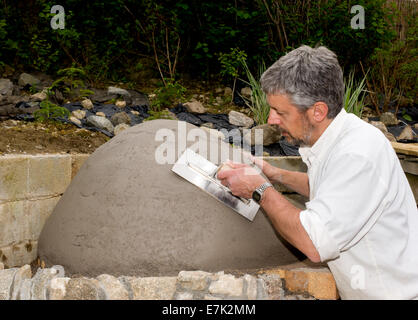 Erde-Ton-Cob-Ofen-Projekt. Die erste Schicht aus Ton-Zettel ist Platz schaffen, was das Innere des Ofens werden umgesetzt Stockfoto