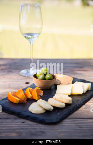 Ein Glas Wein mit Obst, Kekse, Käse und Cracker. Eine traditionelle Weinprobe in einem Sonoma County Weinberg. Stockfoto