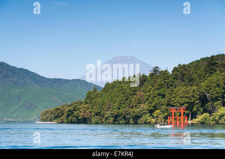 Ein rotes Torii-Tor steht am Ufer des See Ashi mit Mount Fuji in der Ferne. Stockfoto