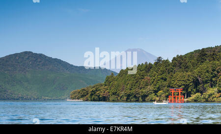 Ein rotes Torii-Tor steht am Ufer des See Ashi mit Mount Fuji in der Ferne. Stockfoto