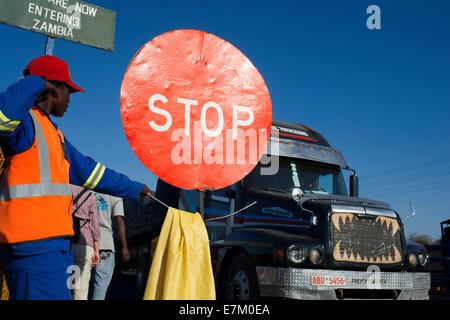 Eine Frau steuert den Datenverkehr zwischen Sambia und Simbabwe.  Ein STOP-Schild zeigt, dass wir Sambia eintreten. Heute eines der V Stockfoto