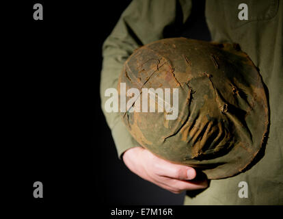 Vietnam-Krieg Periode amerikanischen GI Soldat, hält seine getarnten M1 Helm, vor einem schwarzen Hintergrund. Stockfoto