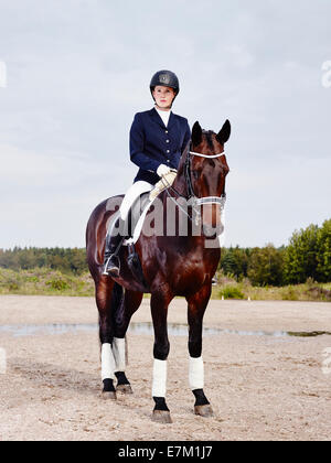 Braune Pferd und schöne Frau mit Pferd-Reiten-Bekleidung Stockfoto