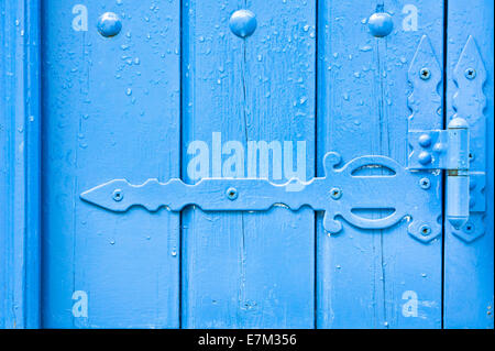 Dekorative Scharnier auf einem blau bemalte Holztür mit Regen fällt Stockfoto