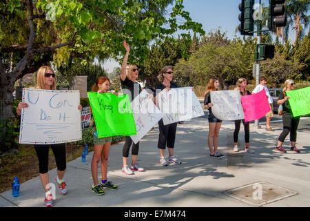 Stehend an einer Straßenecke und unterstützende Zeichen halten, fördern Freiwillige in einem Charity Fundraising Spaziergang in Tustin, Kalifornien, Demonstranten, ihre Reise fortzusetzen. Stockfoto