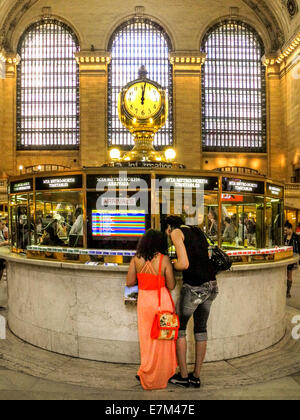 Ein bunt gekleideten jungen Paar lesen einen Zeitplan am Infostand des New Yorker Grand Central Station. Hinweis berühmten Uhr. Stockfoto