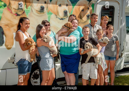 Einem glücklichen Gruppe in Midway City, CA, geliefert Pose neu umarmt reinrassige Labrador Welpen an der Tür des LKW"Welpen" von der Organisation Führhunde für Blinde. Verbringen sie 15 Monate Erziehung und Ausbildung des Hundes, bevor es für zurückgegeben werden müssen Stockfoto