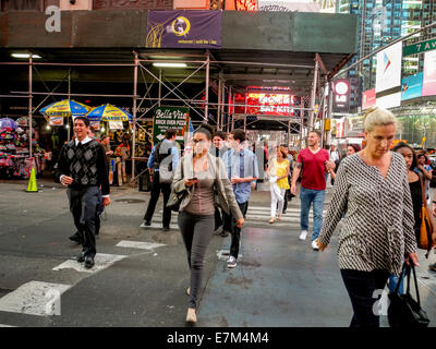 Fußgänger von unterschiedlichen Alters überqueren eine Straße in Times Square in New York City. Beachten Sie die Gebäude im Bau und Sabrett Hot-Dog Pushcart Anbieter im Hintergrund. Stockfoto