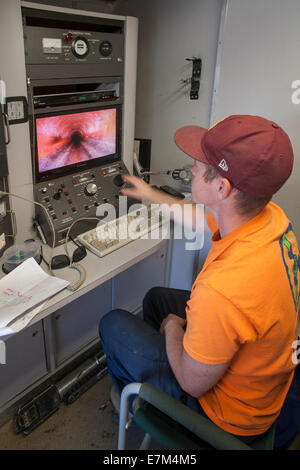 Mit einer Fernbedienung TV-Kamera, inspiziert ein Klempner das Innere einer Regenrinne für Lecks in Laguna Niguel, CA. Stockfoto