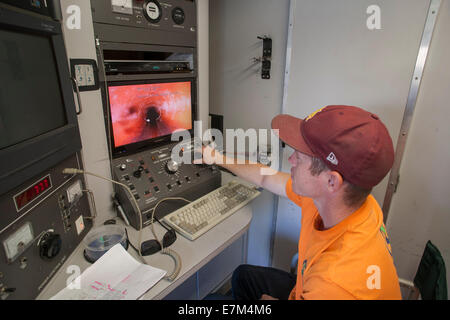 Mit einer Fernbedienung TV-Kamera, inspiziert ein Klempner das Innere einer Regenrinne für Lecks in Laguna Niguel, CA. Stockfoto