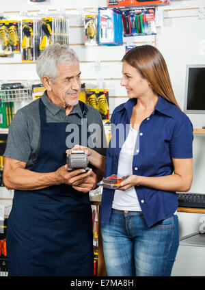 Weibliche Kunden zahlen über Smartphone im Baumarkt Stockfoto