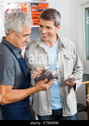 Kunden zahlen Durch Smartphone in Hardware Store Stockfoto