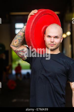Mann mit Langhantel Platte im Fitnessstudio fit Stockfoto