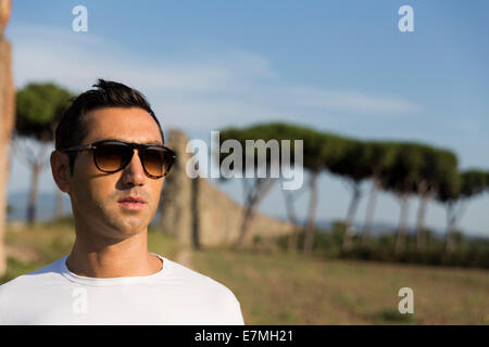 Mann mit Sonnenbrille und ein weißes T-shirt, Blick auf den Horizont. Sieben Aquädukte und Umgebung, Via Appia Antica, Rom, Italien Stockfoto