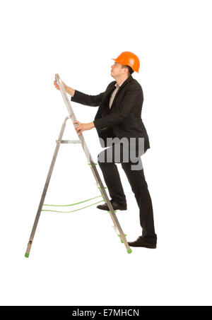 Junge männliche Ingenieur auf schwarzen Anzug und Orange Helm posiert auf tragbaren Leiter. Unter Betonung hinauf. Auf vollen weißen Hintergrund isoliert... Stockfoto