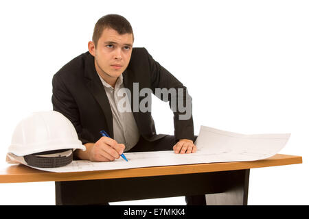Nachdenkliche junge Architekt oder Ingenieur sitzen, arbeiten auf einer Blaupause an einem Tisch starrt sinnend in die Luft, isoliert auf whi Stockfoto