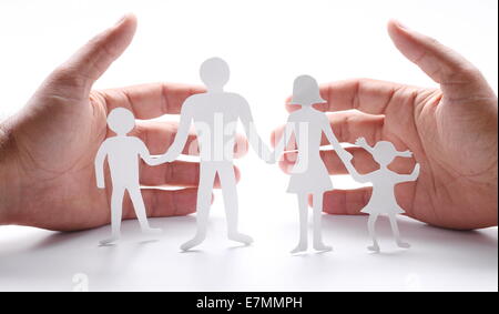 Pappfiguren der Familie auf einem weißen Hintergrund. Das Symbol der Einheit und des Glücks. Händen umarmen sanft die Familie. Stockfoto