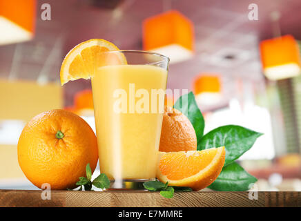 Orange Früchte und ein Glas Orangensaft auf Holztisch. Stockfoto