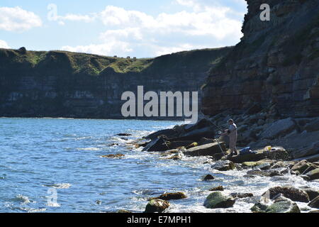 Mann auf Felsen in der Bucht Angeln Stockfoto