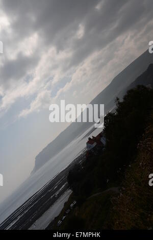 Wenig Licht über Küste mit dunklen Wolken Robin Hoods bay Stockfoto