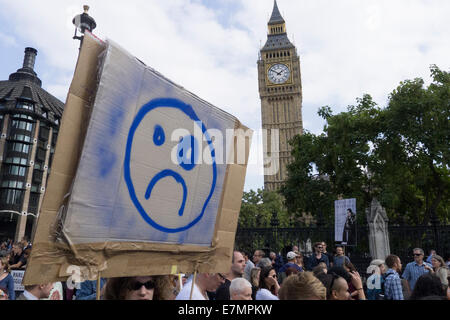 Eine Demonstrantin hält ein Karton Plakat mit einem sauertöpfischen Gesicht und ein schwarzes Auge, als sie den Turm von Big Ben während der Klimawandel Demonstration, London, 21. September 2014. © Sue Cunningham Stockfoto