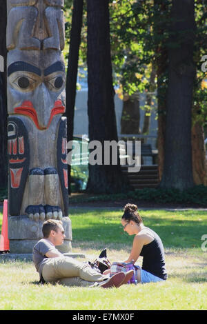 Junge Liebhaber in einem Park entspannen. Totempfahl im Hintergrund. Stockfoto