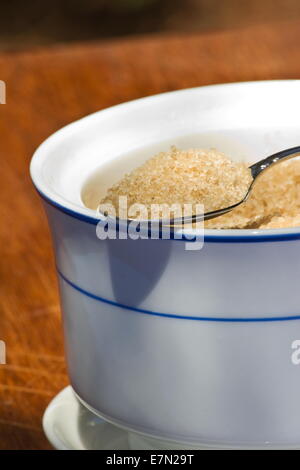 Brauner Zucker in einem Löffel und Sugar Bowl auf hölzernen Hintergrund Stockfoto