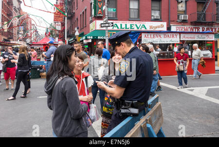 Drei junge asiatische Frauen bitten, eine weiße NYPD officer für lokale Richtungen an der New York City San Gennaro fest Stockfoto