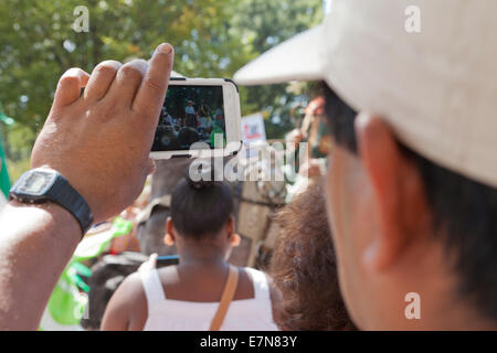 Mann für Videoaufnahmen der Veranstaltung bei einem Outdoor-Festival mit Smartphone - USA Stockfoto