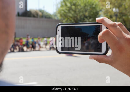 Mann für Videoaufnahmen der Veranstaltung bei einem Outdoor-Festival mit Smartphone - USA Stockfoto