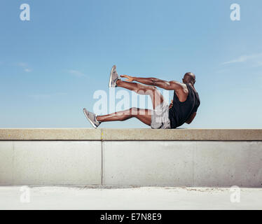 Starker junger Mann Bewegung in der Natur. Muskulösen jungen Fitness-Modell gegen Himmel trainieren. Stockfoto