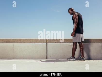 Bild muskulösen jungen Mann auf einem Steg, immer bereit für seinen Lauf. Konzentrierte sich männliche Athlet Vorbereitung für seine laufenden Training im freien Stockfoto