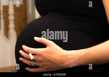 Schwangere Frau hält eine Zigarette Stockfoto