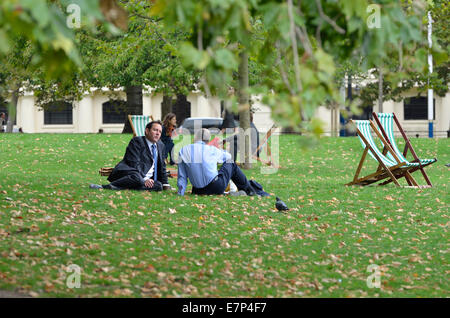 London, England, Vereinigtes Königreich. Zwei Geschäftsleute entspannen auf dem Rasen im Green Park Stockfoto