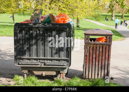 Große Mülltonne neben einem Abfallbehälter, beide Fächer voll mit Müll in einem Park in London, England, Großbritannien Stockfoto