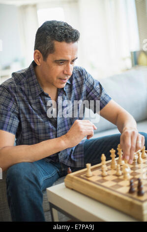 Mann spielt Schach im Wohnzimmer Stockfoto