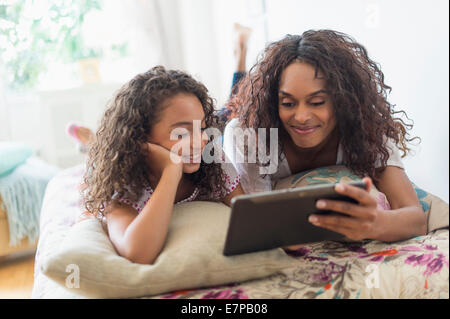Mutter mit Tochter (8-9) mit digital-Tablette auf Bett Stockfoto