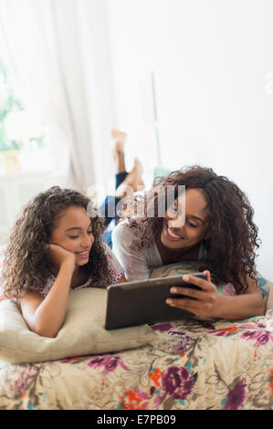 Mutter mit Tochter (8-9) mit digital-Tablette auf Bett Stockfoto