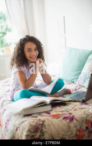Mädchen (8-9) studieren auf Bett Stockfoto