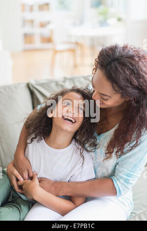 Mutter umarmt Tochter im Wohnzimmer (8-9) Stockfoto