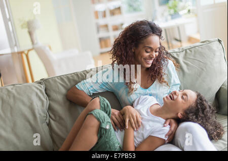 Mutter Tochter (8-9) auf Sofa kitzeln Stockfoto