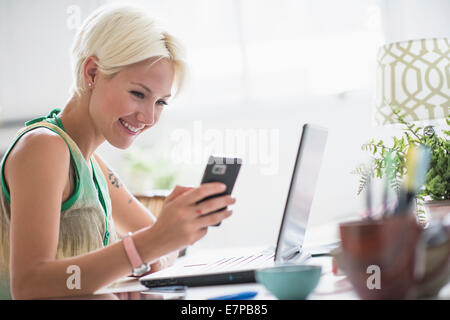 Frau mit Handy und Laptop zu Hause Stockfoto