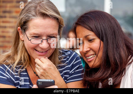 Zwei Frauen, die Fotos auf einem Smartphone, Hartfield Village Fete, Sussex, England Stockfoto