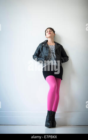 Frau trägt Lederjacke, Minirock und Ping Strumpfhosen Stockfoto