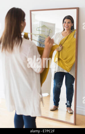 Frau hält neuen Kleid und mit Blick auf Spiegel Stockfoto